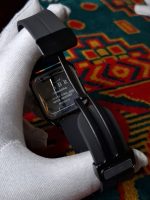 Back view of the SABR 1037B Full Black watch, showing the stainless steel case back and black strap held by a gloved hand.