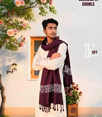 A man wearing a long white tunic styles a deep red Arabic calligraphy shawl with white script and fringed ends.