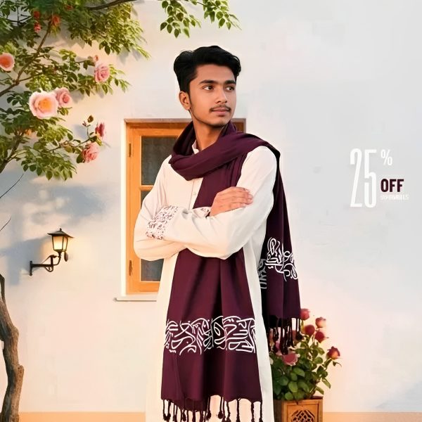 A man wearing a long white tunic styles a deep red Arabic calligraphy shawl with white script and fringed ends.