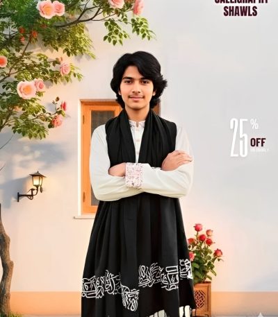 A young man models a black shawl decorated with white Arabic calligraphy and a tasseled fringe.