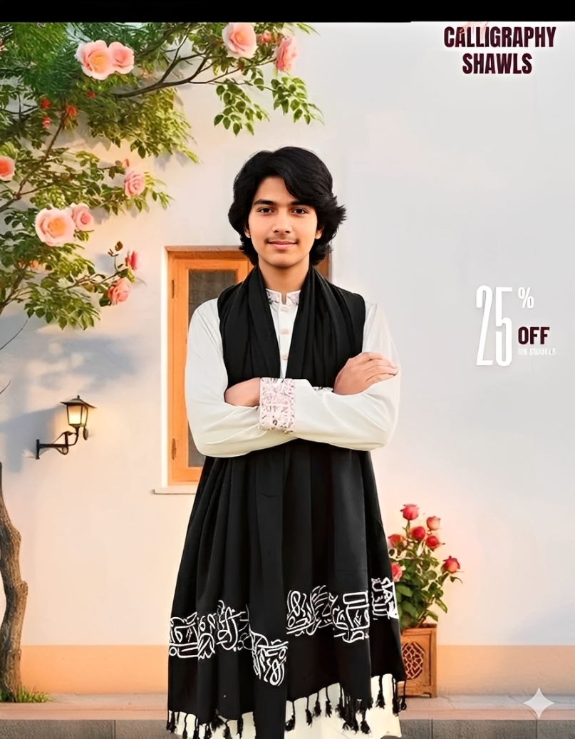 A young man models a black shawl decorated with white Arabic calligraphy and a tasseled fringe.
