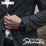 A man wearing the black stainless steel SKMEI 1260 quartz watch while adjusting his dark grey suit jacket.