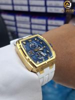 A close-up of the CURREN 8488 men's chronograph watch with a gold case, blue dial, and white strap worn on a wrist.