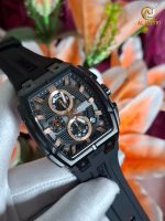A gloved hand holding a black and rose-gold CURREN 8488 men's square chronograph watch against a floral background.