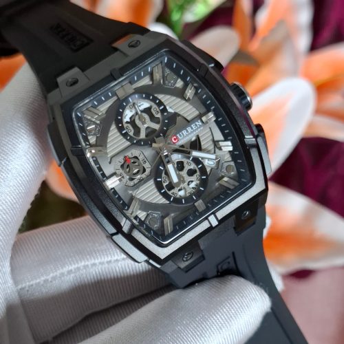 A person wearing a white glove holds the CURREN 8488 Square Chronograph Men's Watch, showing its black case and silver dial.