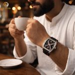 A man wearing the SKMEI 9364 Luminous Hollow watch while holding a white coffee cup in a cafe setting.