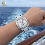 A person wearing the SKMEI 9364 Men's Watch with a white strap and silver case, overlooking the ocean from a boat.