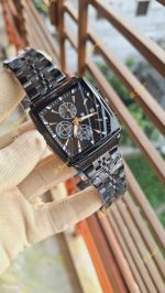 A gloved hand holding the POEDAGAR 866 luxury square wristwatch, showing its black dial with gold details and black metal strap.