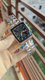 A gloved hand holding the POEDAGAR 866 luxury square business wristwatch with its green dial and two-tone silver and gold band.