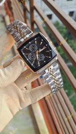 A person wearing a glove holds up a POEDAGAR 866 luxury square wristwatch with a two-tone silver and gold band and a black face.