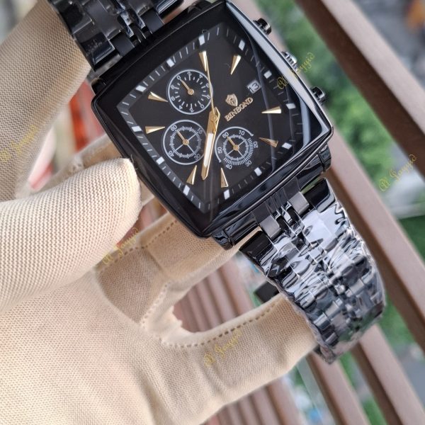 A hand in a beige glove holds up a Binbond 911 Original Men’s Luxury Watch with a square black case and gold accents.