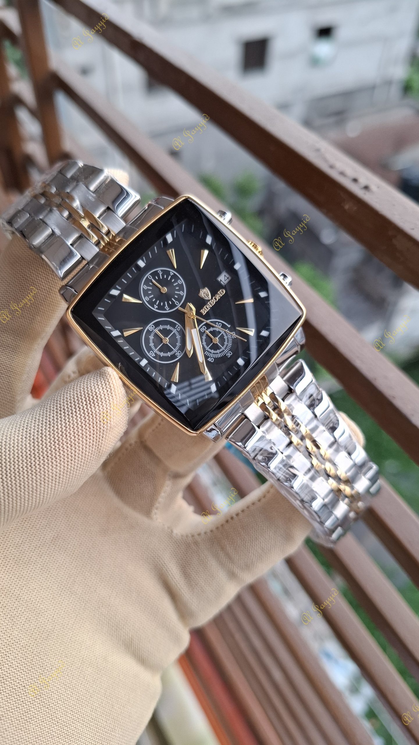 A gloved hand holding a Binbond 911 Original Men’s Luxury Watch, showing its square black face and two-tone silver and gold bracelet.
