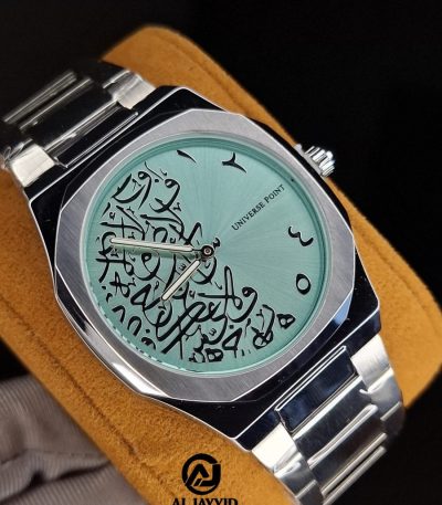 A close-up of the Universe Point Arabic calligraphy watch, featuring a tiffain colored dial and a silver metal band.