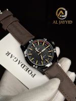 A gloved hand holding a POEDAGAR 895 men's watch, which has a black dial, a black case, and a brown leather strap.