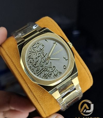 A gold-colored Universe Point watch with a metal bracelet, featuring a grey dial with intricate black Arabic calligraphy.