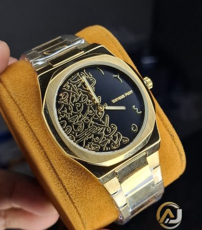 A close-up view of the Universe Point Arabic Calligraphy Watch, showing its gold-toned case and black dial with gold calligraphy.