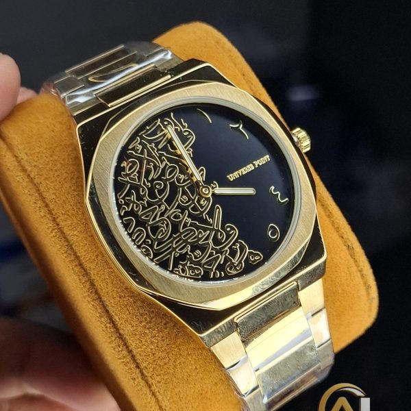 A close-up view of the Universe Point Arabic Calligraphy Watch, showing its gold-toned case and black dial with gold calligraphy.
