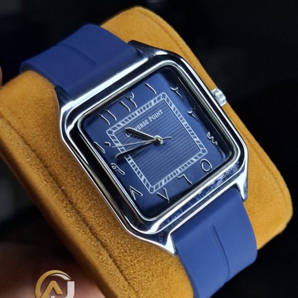 A Universe Point watch with a square, blue dial, Arabic numerals, and a matching blue silicone strap, held on a yellow cushion.