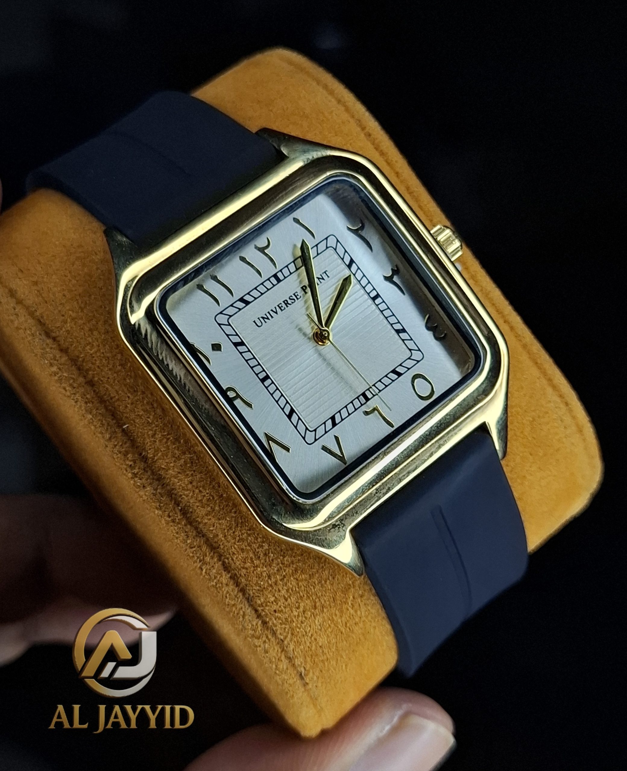 Universe Point Watch with Arabic Numerals A close-up of the Universe Point watch, showing its square gold-tone case, white dial with Arabic numerals, and dark silicone strap.