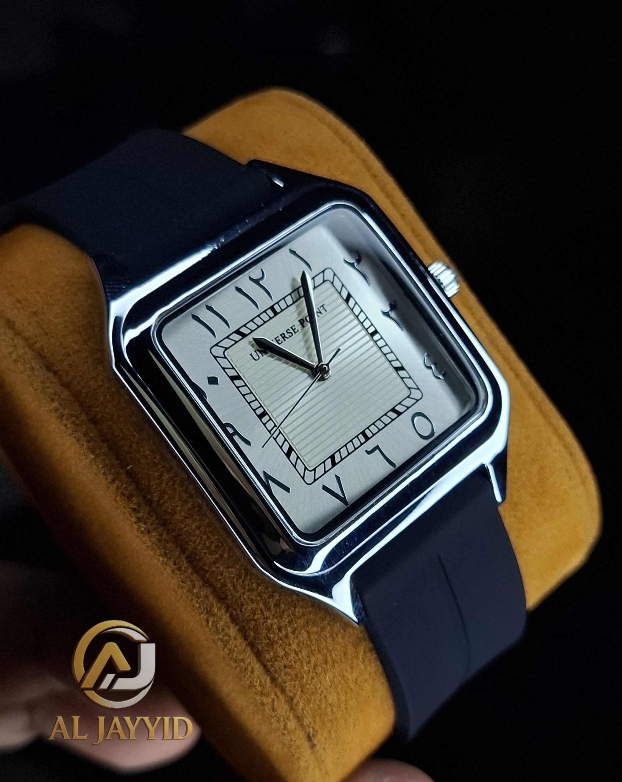 Universe Point Watch with Silicone Strap A Universe Point Watch with a square silver case and a textured white dial with Arabic numerals, shown on a yellow cushion.