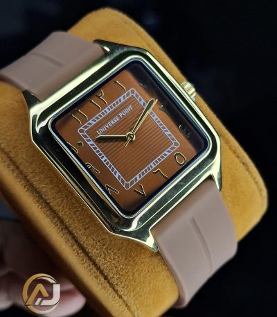 A close-up of the Universe Point Watch, featuring a square gold-tone case, a brown dial with Arabic numerals, and a beige silicone strap.
