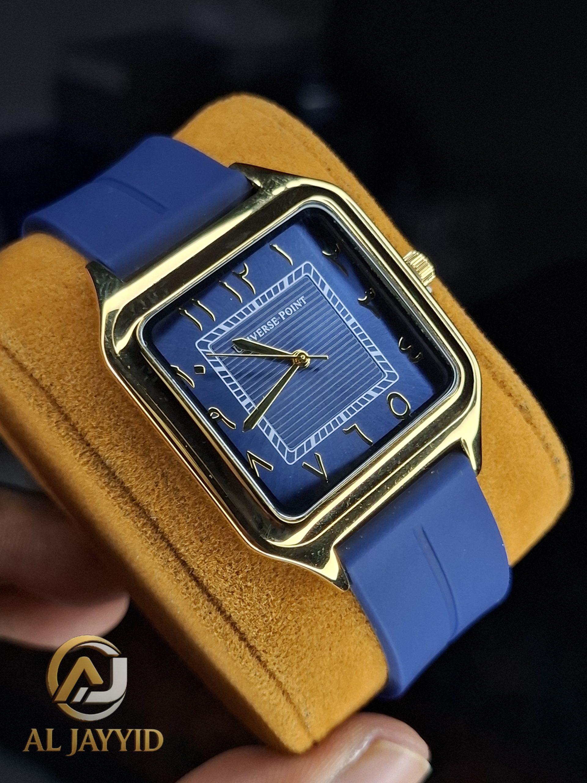 Universe Point Gold & Blue Silicone Watch A Universe Point watch with a square gold case, a dark blue dial with Arabic numerals, and a blue silicone strap, shown angled.