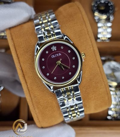 A gloved hand holding the OLIYA 6658 women's watch, showcasing its two-tone silver and gold band and deep red dial.