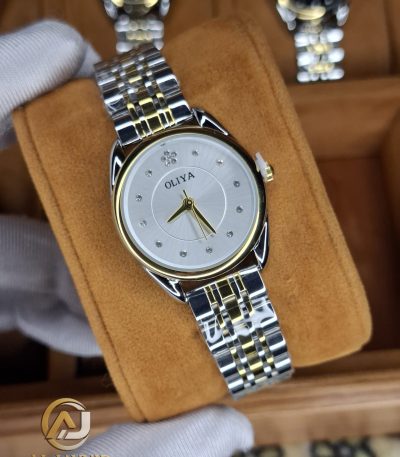 A gloved hand holding an OLIYA 6658 women's two-tone watch with a silver and gold band and a white crystal-studded dial.