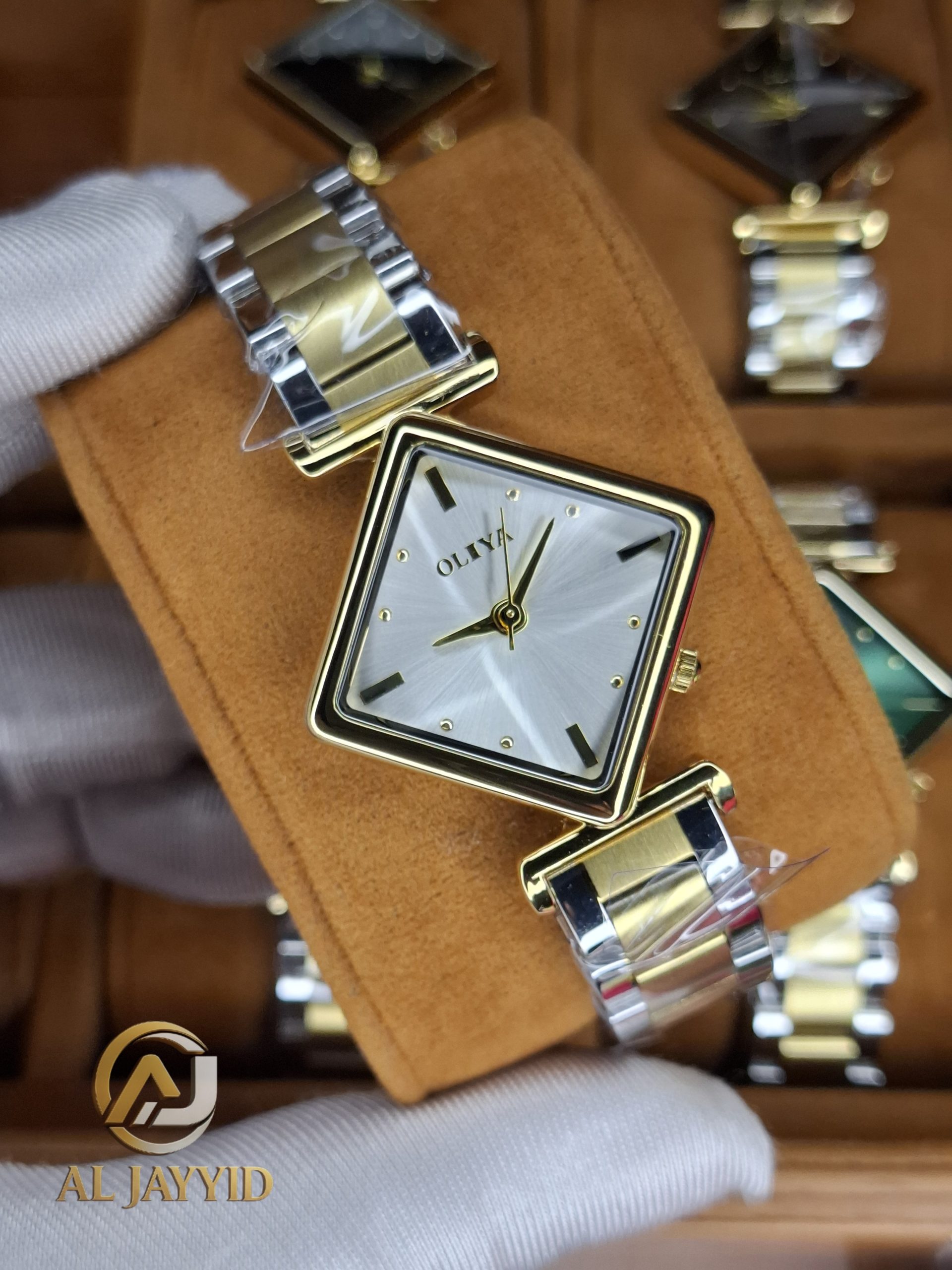 A close-up of the OLIYA 6819 women's two-tone watch, showing its square gold case and silver and gold metal bracelet.