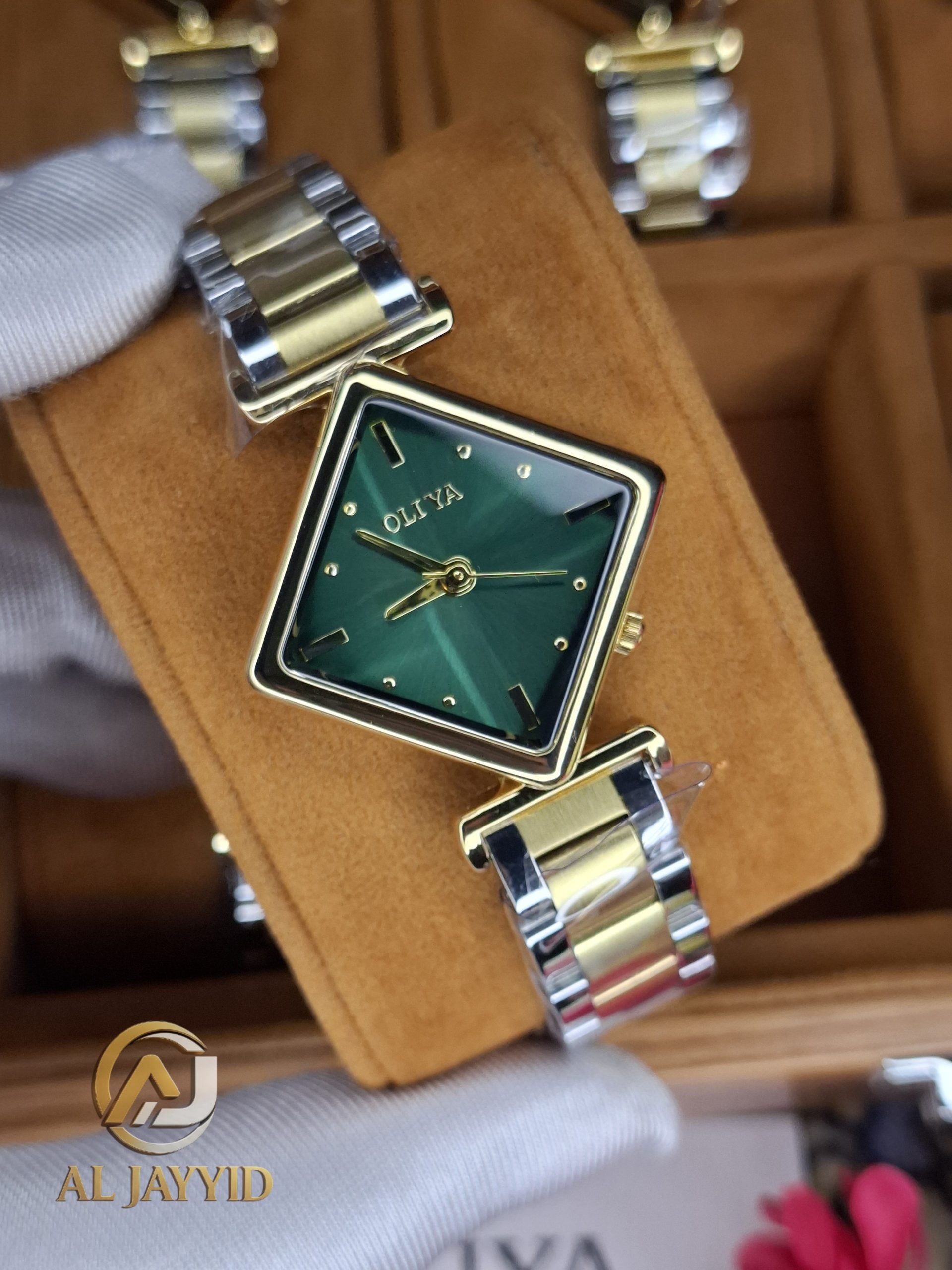 Close-up of the OLIYA 6819 women's watch, showing its square green dial, gold-tone case, and two-tone metal bracelet.