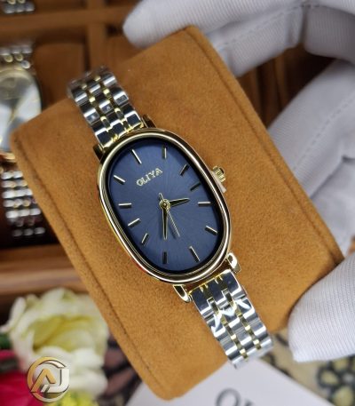 A gloved hand holding an OLIYA 2015 women's watch, featuring a blue oval dial and a two-tone gold and silver bracelet.