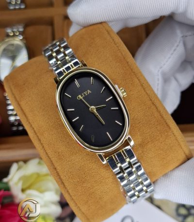 A gloved hand holding an OLIYA 2015 women's watch with an oval black dial and a two-tone silver and gold metal bracelet.