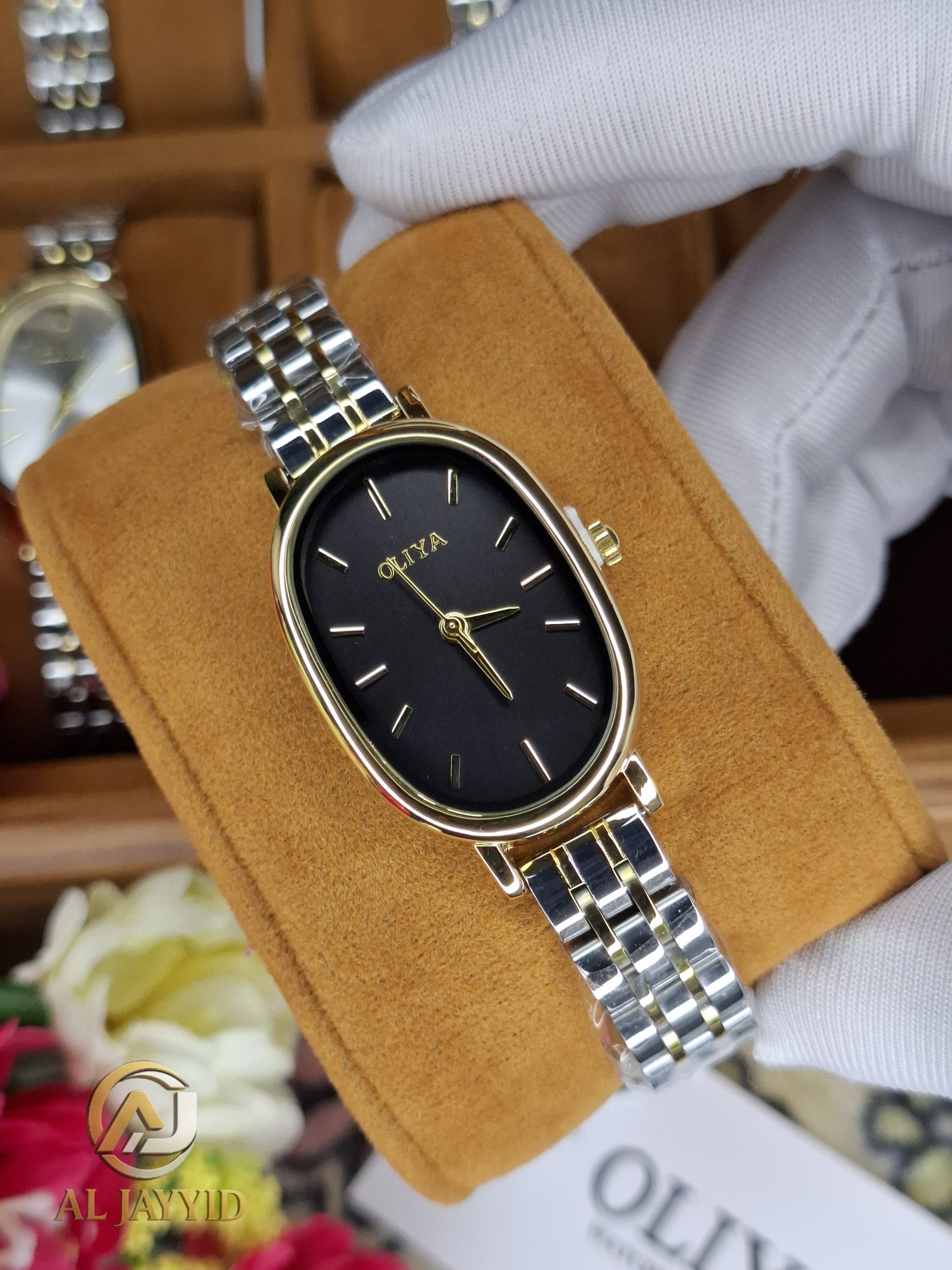 OLIYA 2015 Women's Watch A gloved hand holding an OLIYA 2015 women's watch with an oval black dial and a two-tone silver and gold metal bracelet.