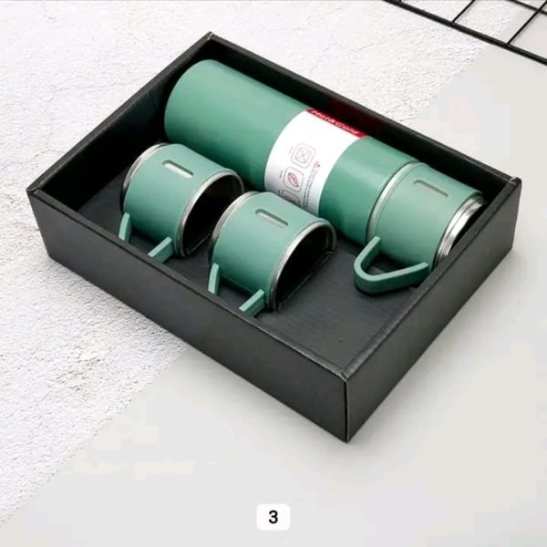 A green vacuum flask set with three matching cups neatly arranged inside a black presentation box.