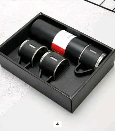 A black Vacuum Flask Set with matching cups displayed neatly inside its presentation box.
