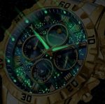 Close-up of the BINBOND 7741 watch with a gold case and a luminous green starry dial.
