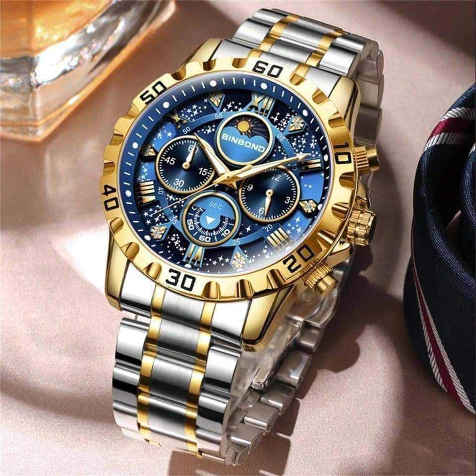 A close-up view of the BINBOND 7741 watch, featuring a blue starry dial, three subdials, and a two-tone gold and silver band.