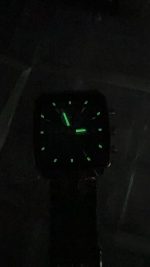A POEDAGAR 866 luxury square business wristwatch with its green luminous hands and hour markers glowing brightly in the dark.