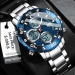 A silver POEDAGAR E102 watch with a blue dial and stainless steel band, shown at an angle on a black surface.