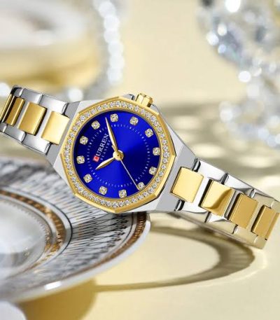A CURREN 9100 ladies watch with a two-tone silver and gold band, a crystal-studded gold bezel, and a vibrant blue dial.