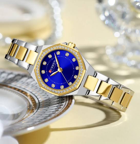 A CURREN 9100 ladies watch with a two-tone silver and gold band, a crystal-studded gold bezel, and a vibrant blue dial.