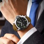 A man wearing the POEDAGAR 859 luxury sports watch with a silver case, black dial, and brown leather strap with a suit.