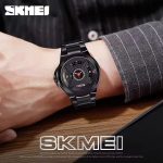 A man wearing the Skmei 1699 X Shape men's wrist watch with a black steel band and a unique black dial with red accents.