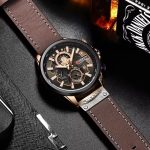 A CURREN 8380 chronograph men's watch with a brown leather strap and rose gold details, displayed on a dark textured surface.