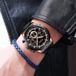 A man's wrist wearing the CURREN 8355 black and gold chronograph watch with a stainless steel band, paired with a black leather jacket.