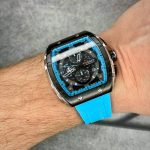 A man's wrist wearing the CURREN 8442 chronograph watch which features a black and blue case and a sky blue silicone band.