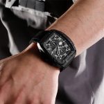 A man's wrist wearing the black Naviforce 8052T watch with a silicone band and chronograph face.