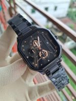 A hand in a white glove holding a black Poedagar 628 men's watch with a stainless steel strap and a square-shaped face.