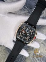 A gloved hand holds the CURREN 8442 chronograph men's watch, showing its rose gold and black case and black silicone band.