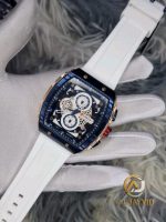 A gloved hand holding a CURREN 8442 chronograph sports watch with a white silicone band and a blue and gold square face.